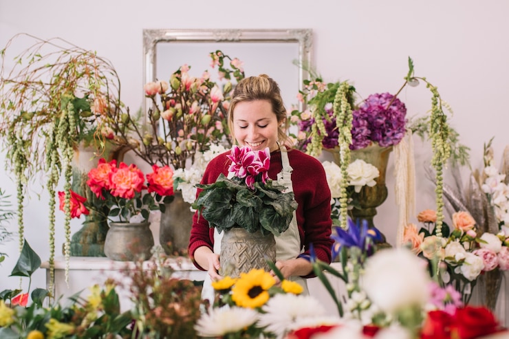 Foto gratuito fiorista emozionante che odora i fiori in negozio