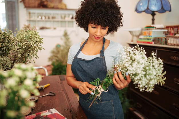 Fiorista femminile africano che esamina mazzo di fiori bianchi