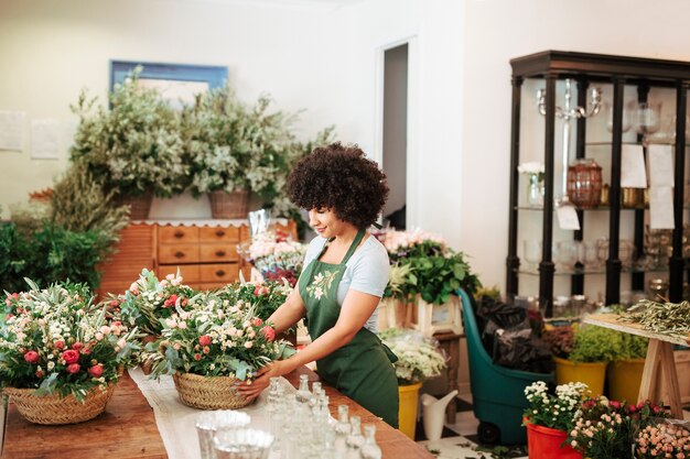 Fiorista femminile che organizza cesto di fiori nel negozio floreale