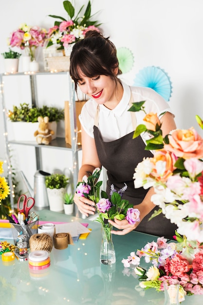 Fiorista femminile felice che ordina i fiori in vaso