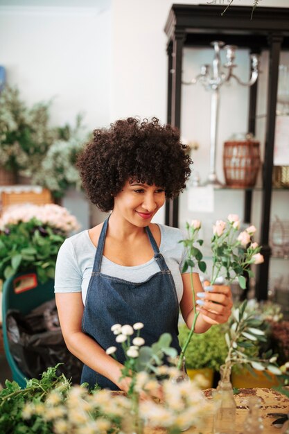 Fiorista femminile sorridente che sistema i fiori in vaso di vetro