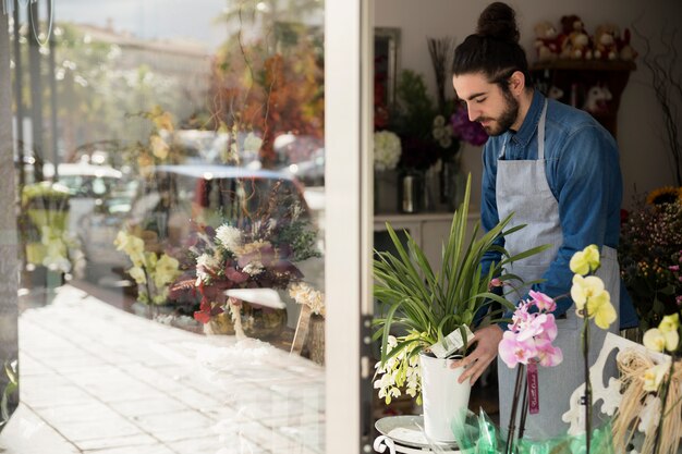 Fiorista maschio che organizza il vaso di fiori nel suo negozio