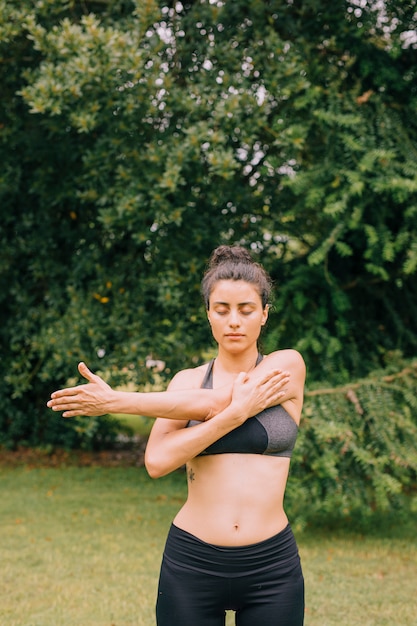 Fitness donna riscaldamento allungando le braccia prima esercizi al parco