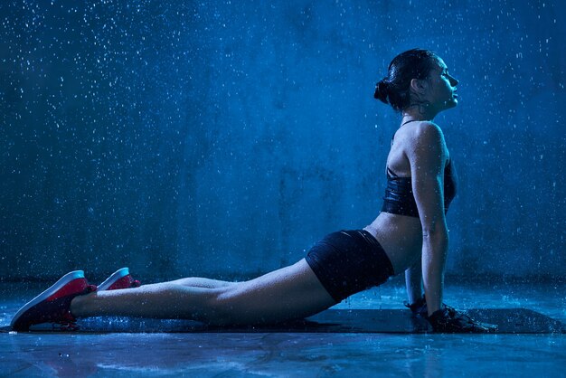 Fitnesswoman a praticare yoga sotto la pioggia