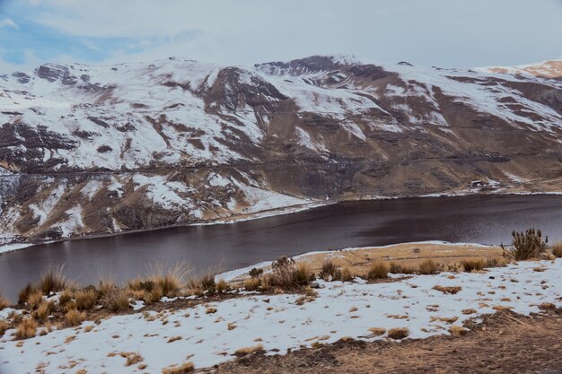 Fiume che scorre circondato dalle alte montagne coperte di neve in inverno