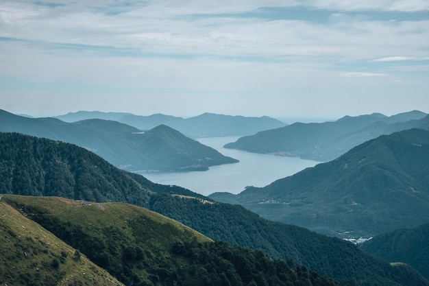 Fiume circondato da colline coperte di foreste e nebbia sotto il cielo nuvoloso e la luce del sole