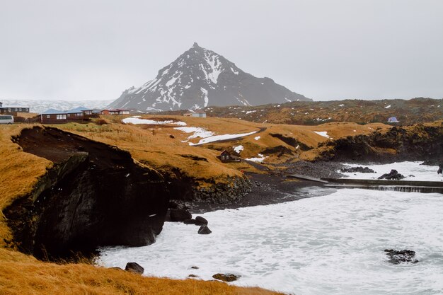 Fiume circondato da colline ricoperte di vegetazione e neve in un villaggio in Islanda