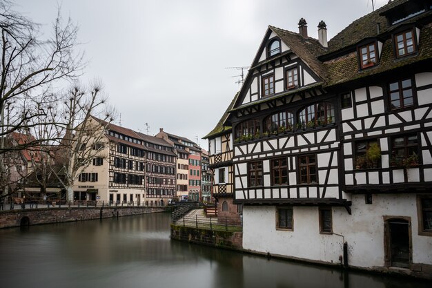 Fiume circondato da edifici colorati e vegetazione sotto un cielo nuvoloso a Strasburgo in Francia