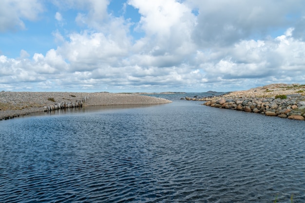 Fiume circondato da rocce sotto la luce del sole e un cielo nuvoloso durante il giorno