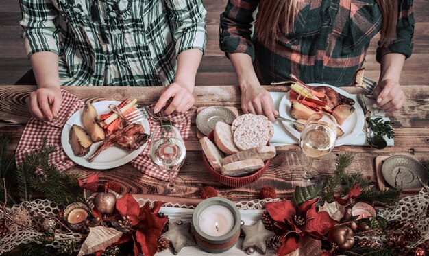 Flat-lay di mani di amici che mangiano e bevono insieme. Vista dall'alto di persone che hanno festa, si riuniscono, celebrano insieme al tavolo rustico in legno con diversi snack di vino e fingerfood