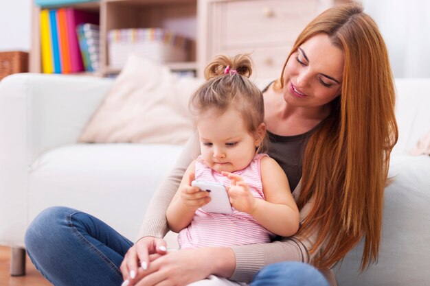 Focus carino bambina imparare utilizzando il telefono cellulare