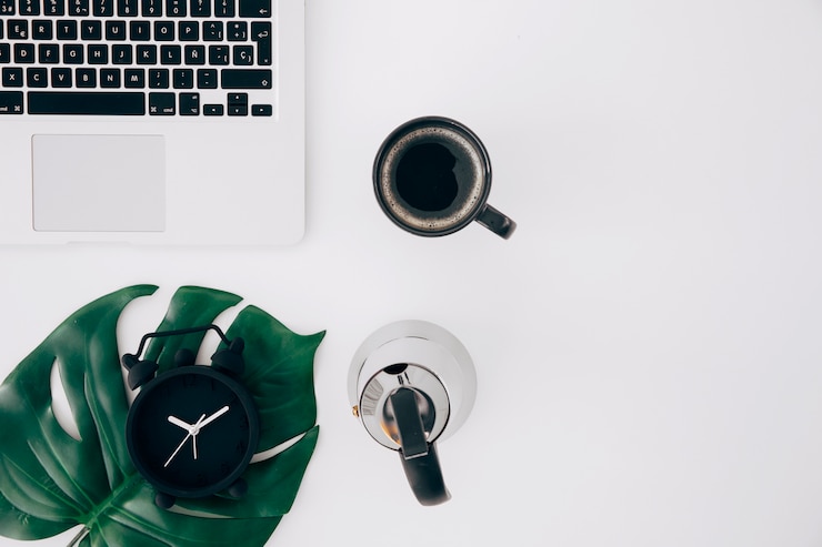 Foto gratuito foglia di mostro su sveglia; bollitore; tazza di caffè e laptop su sfondo bianco
