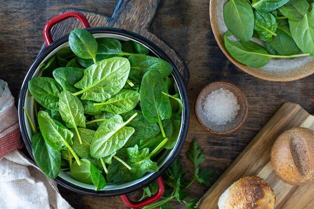 Foglie di spinaci freschi in una ciotola e ingredienti per preparare l'insalata