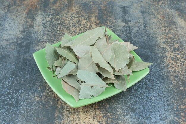 Foglie di tè verde sul piatto verde.