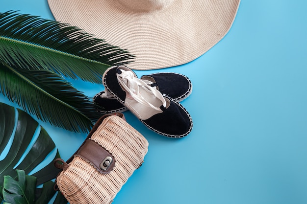 Foglie tropicali su uno sfondo blu con accessori estivi. Il concetto di vacanze estive.