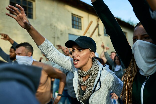 Folla furiosa di persone che protestano per i diritti umani per le strade Il focus è sulla donna caucasica con il braccio alzato