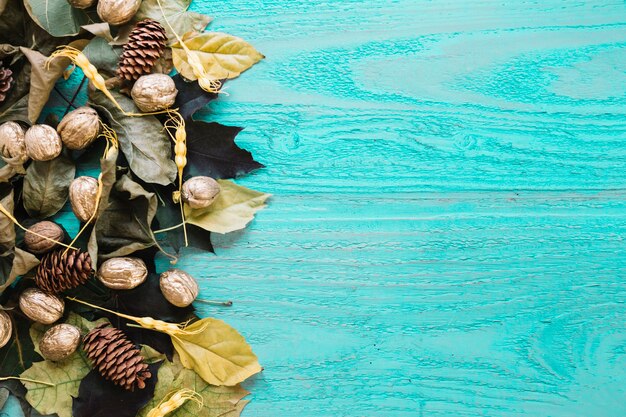 Fondo di legno blu di autunno con le foglie, le pigne e le noci