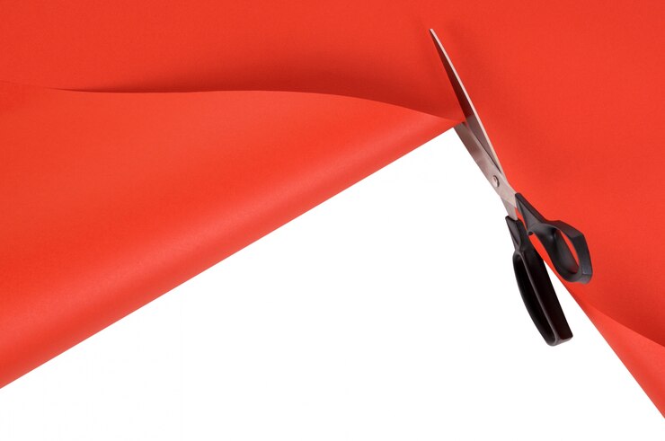 Foto gratuito forbici che tagliano carta sfondo rosso