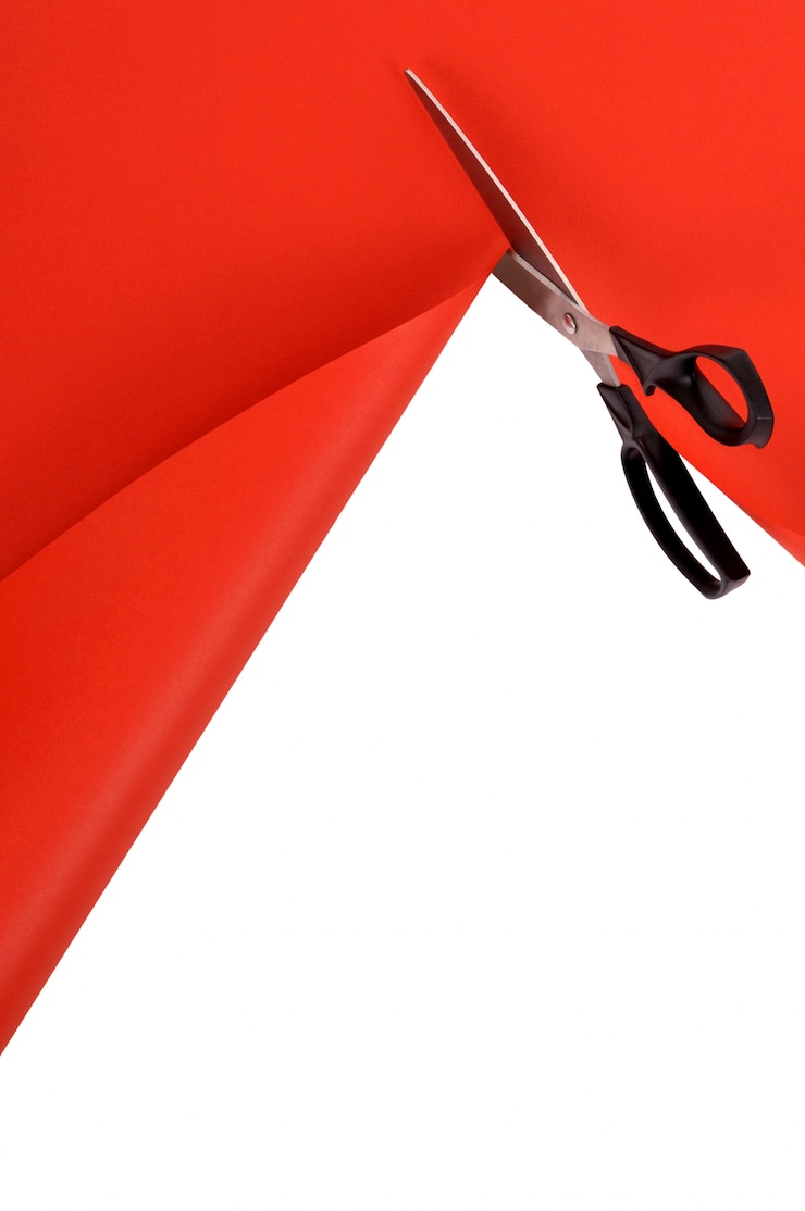 Foto gratuito forbici che tagliano carta sfondo rosso