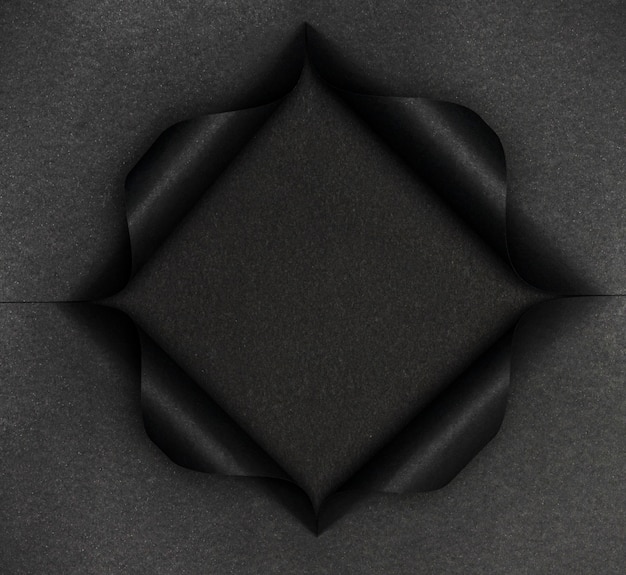 Forma nera astratta su carta nera strappata