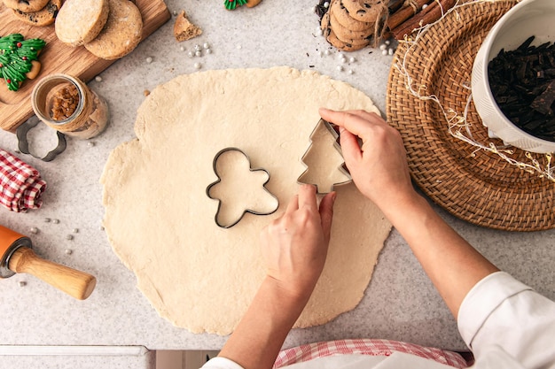 Forma per i biscotti di Natale nelle mani delle donne sullo sfondo dell'impasto