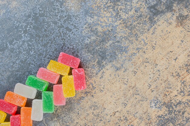 Forma quadrata gelatina di caramelle sapore di frutta su uno sfondo scuro. Foto di alta qualità