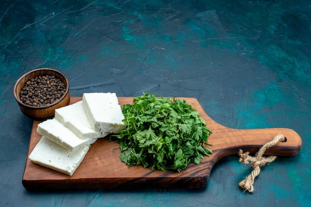 Formaggio bianco vista frontale con verdure fresche su sfondo blu scuro.