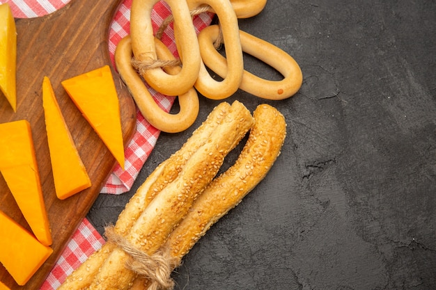 Formaggio fresco a fette vista dall'alto con panini e cracker su sfondo grigio scuro