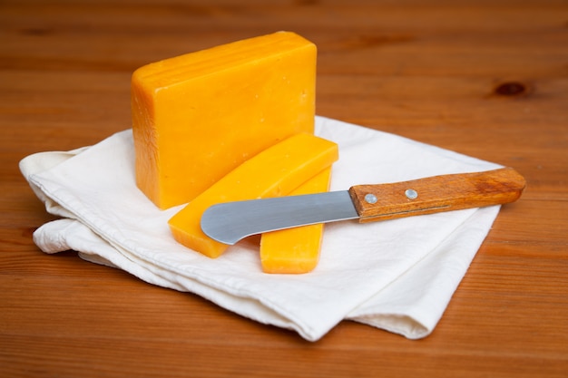 Formaggio giallo e coltello che mettono su panno bianco