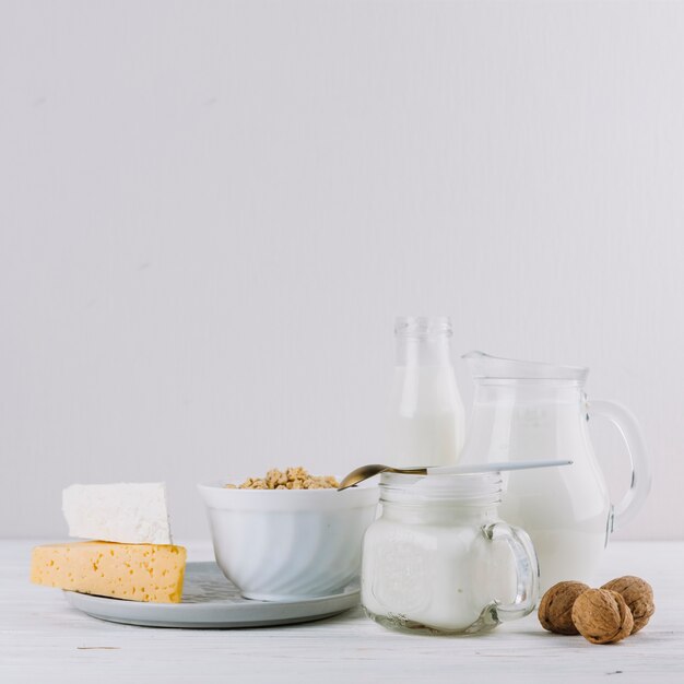 Formaggio; latte; ciotola di cereali e noci su sfondo bianco