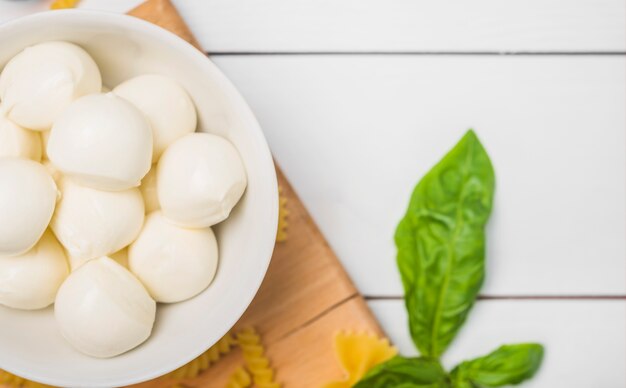 Formaggio mozzarella italiana tradizionale nella ciotola con foglie di basilico