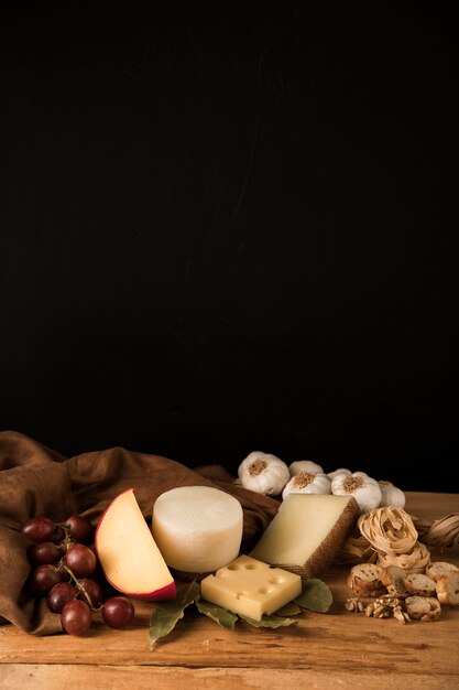 Formaggio, uva, aglio e snack salutare su sfondo nero