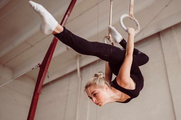 Formazione atletica della donna di angolo basso sugli anelli di ginnastica