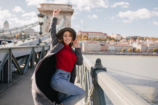 Formosa donna sognante divertente in posa sul ponte sullo sfondo del fiume