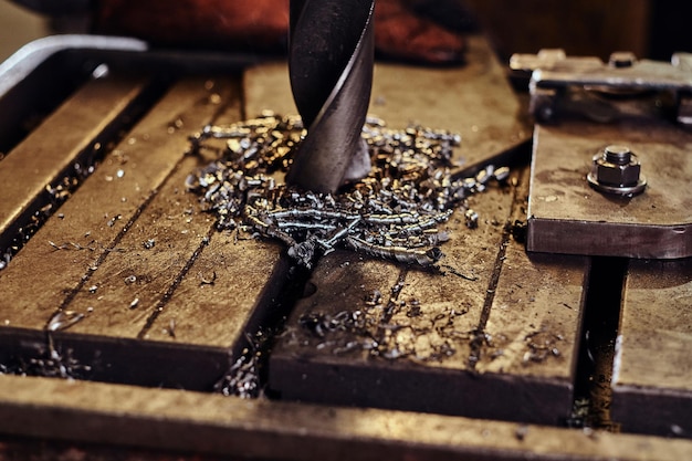 Foro di perforazione nel metallo con trapano gigante in fabbrica di acciaio da parte di un lavoratore maschio.