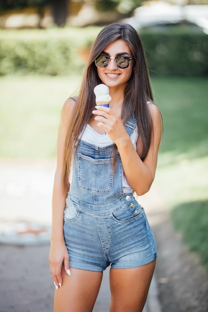 Foto a grandezza naturale di una ragazza che indossa jeans combinaison fuori nell'estate diurna della città