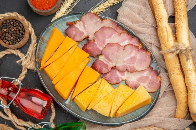 Foto ad alta risoluzione di deliziosi snack bottiglie cadute peperoni su asciugamano e corda su sfondo nero