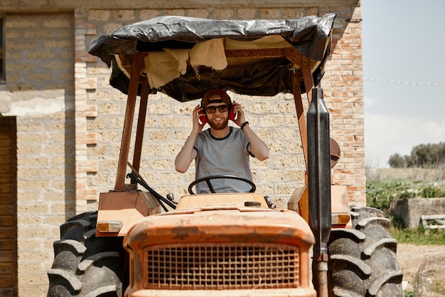 Foto all'aperto di bello allegro giovane barbuto agricoltore indossando occhiali da sole