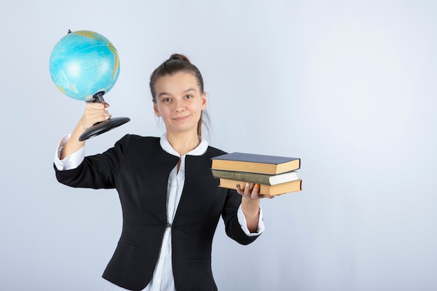 Foto del giovane insegnante che tiene libri e globo su bianco.