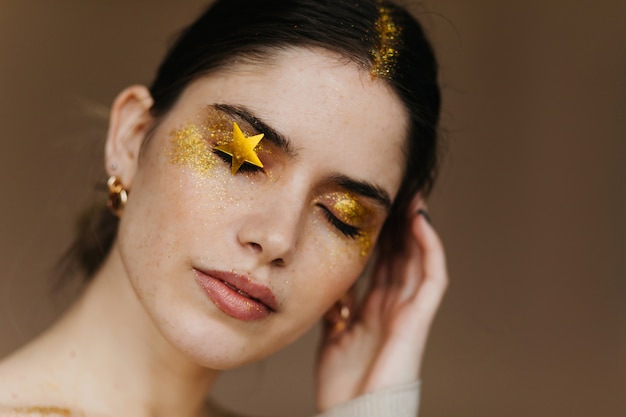 Foto del primo piano dell'incantevole signora dai capelli neri in posa con gli occhi chiusi. affascinante ragazza con trucco da festa.