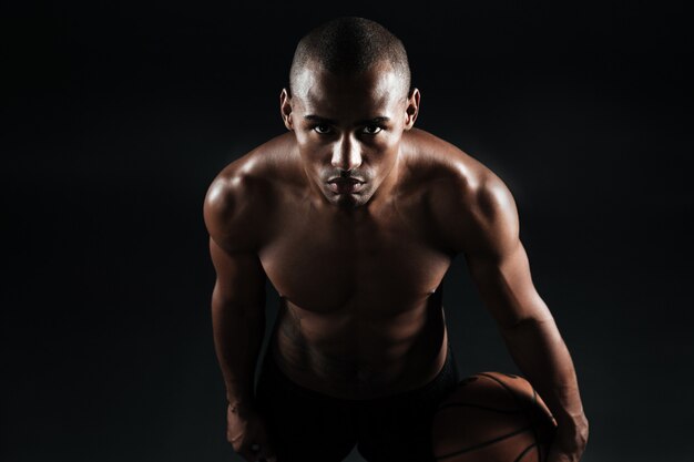 Foto del primo piano della palla afroamericana della tenuta del giocatore di pallacanestro