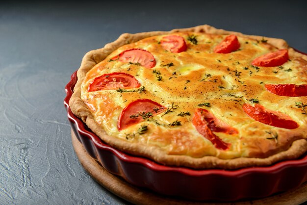 Foto del primo piano della torta classica della quiche lorraine con i pomodori