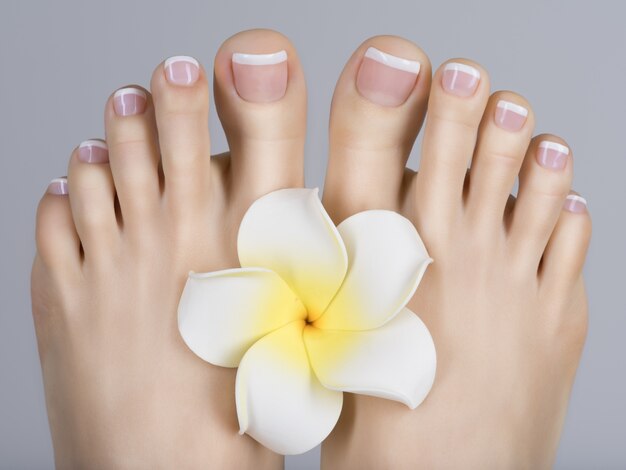 Foto del primo piano di un piede femminile con il pedicure francese bianco sulle unghie