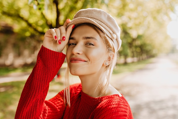 Foto del primo piano di una splendida donna bionda con trucco naturale e sorriso affascinante. Bella ragazza in un bel maglione elegante