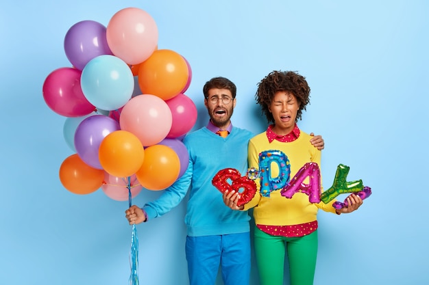 Foto della giovane coppia scontenta a una festa in posa con palloncini