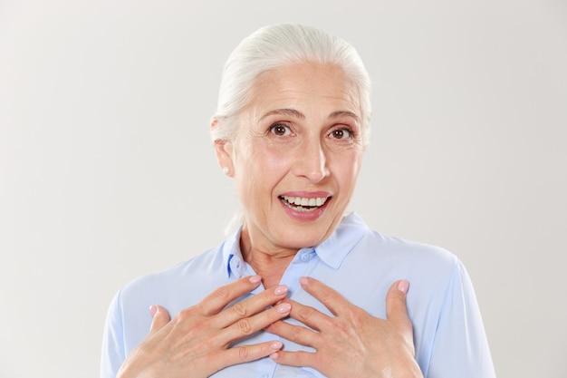 Foto della signora anziana sorpresa con le mani sul suo petto