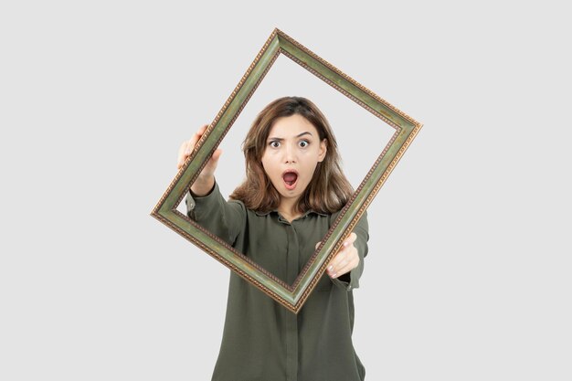 Foto di adorabile modello femminile in piedi nel mezzo della cornice vuota. Foto di alta qualità