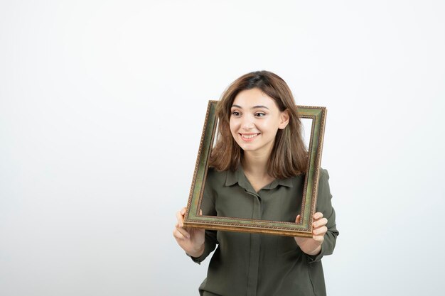 Foto di adorabile modello femminile in piedi nel mezzo della cornice vuota. Foto di alta qualità