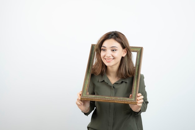 Foto di adorabile modello femminile in piedi nel mezzo della cornice vuota. Foto di alta qualità