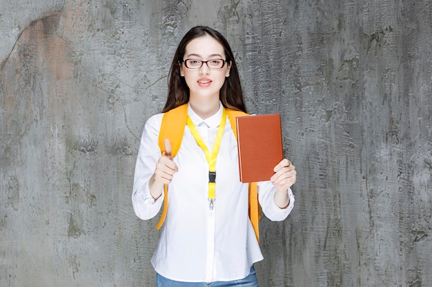 Foto di bella ragazza con gli occhiali in posa con il libro. Foto di alta qualità